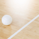 Volleyball ball and white line on wooden court.